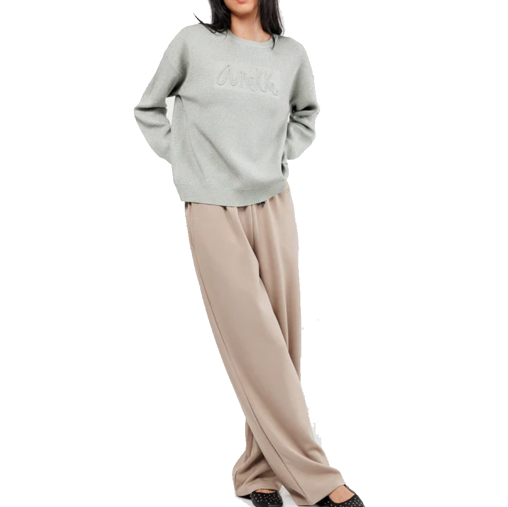 Donna indossa pantalone beige e maglione grigio in posa di contesto d'uso